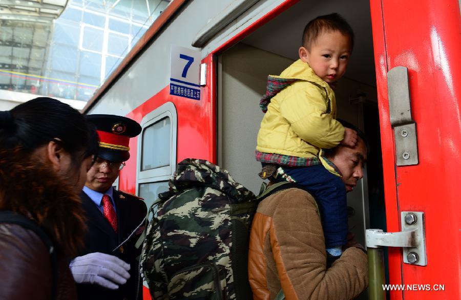 A man carrying a boy boards a train at the Kunming Railway Station in Kunming, capital of southwest China's Yunnan Province, Jan. 19, 2014. China has kicked off its annual Lunar New Year travel rush period, with more than 3.62 billion trips expected to be made on roads, and via trains, planes and ships around the Spring Festival, which falls on Jan. 31 this year. (Xinhua/Wang Jianyun) 