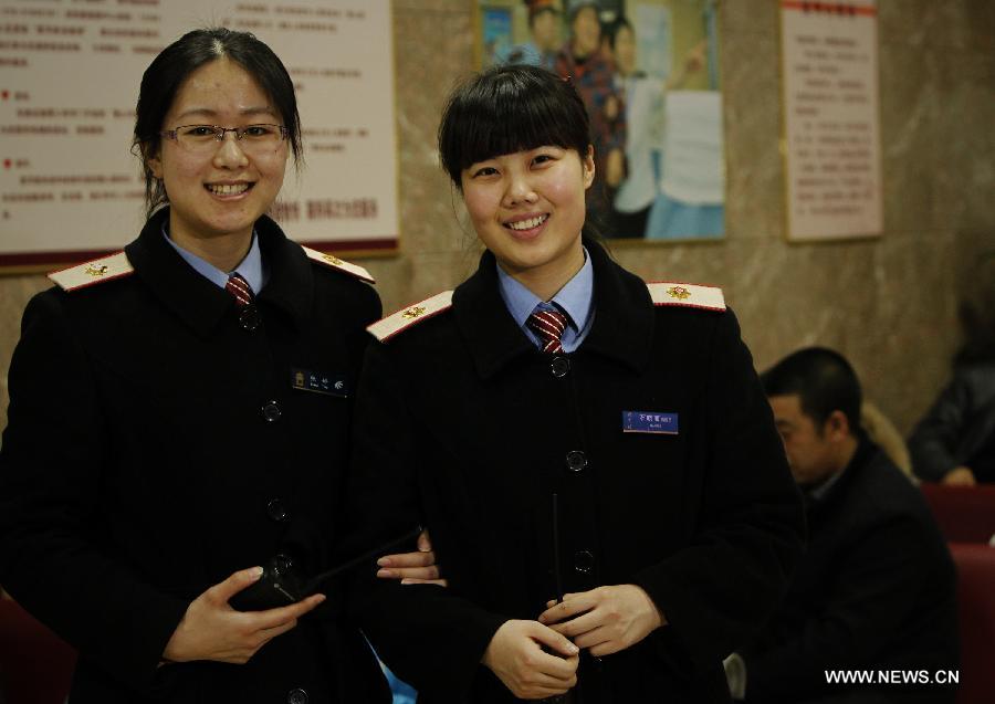 Photo taken on late night Jan. 26, 2014 shows Zhang Ting (L) and Shi Xiaoli, members of a service group mainly in charge of serving infirm passengers at Beijing Railway Station. As the 2014 Chinese lunar new year approaches, a travel peak has been witnessed during the last weekend before the upcoming festival. Railway personnel have been working around the clock during the peak. (Xinhua/Xing Guangli) 