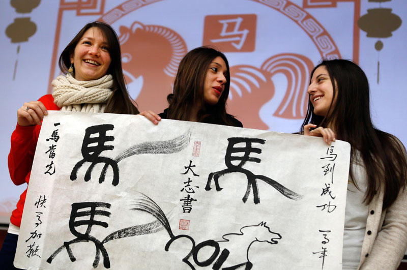 Pilar de Borbon from Argentina, Fressy Garcia from Costa Rica and Aymara Balbi from Argentina display calligraphy skills, with the Chinese character for "horse", at Beijing Language and Culture University on Jan 29, two days before Lunar New Year's Day. (Source: China Daily) 