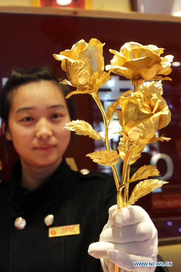 A salesgirl shows a gold rose at a gold shop in Lianyungang City, east China's Jiangsu Province, Feb. 9, 2014. As the valentine's day draws near, roses made of pure gold has become popular among customers despite of its high price. (Xinhua/Si Wei)