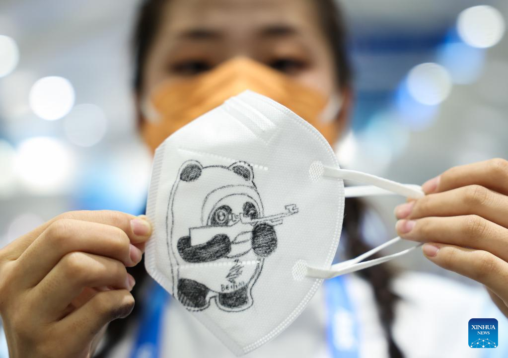 Volunteer paints by hand Bing Dwen Dwen on masks at Beijing 2022