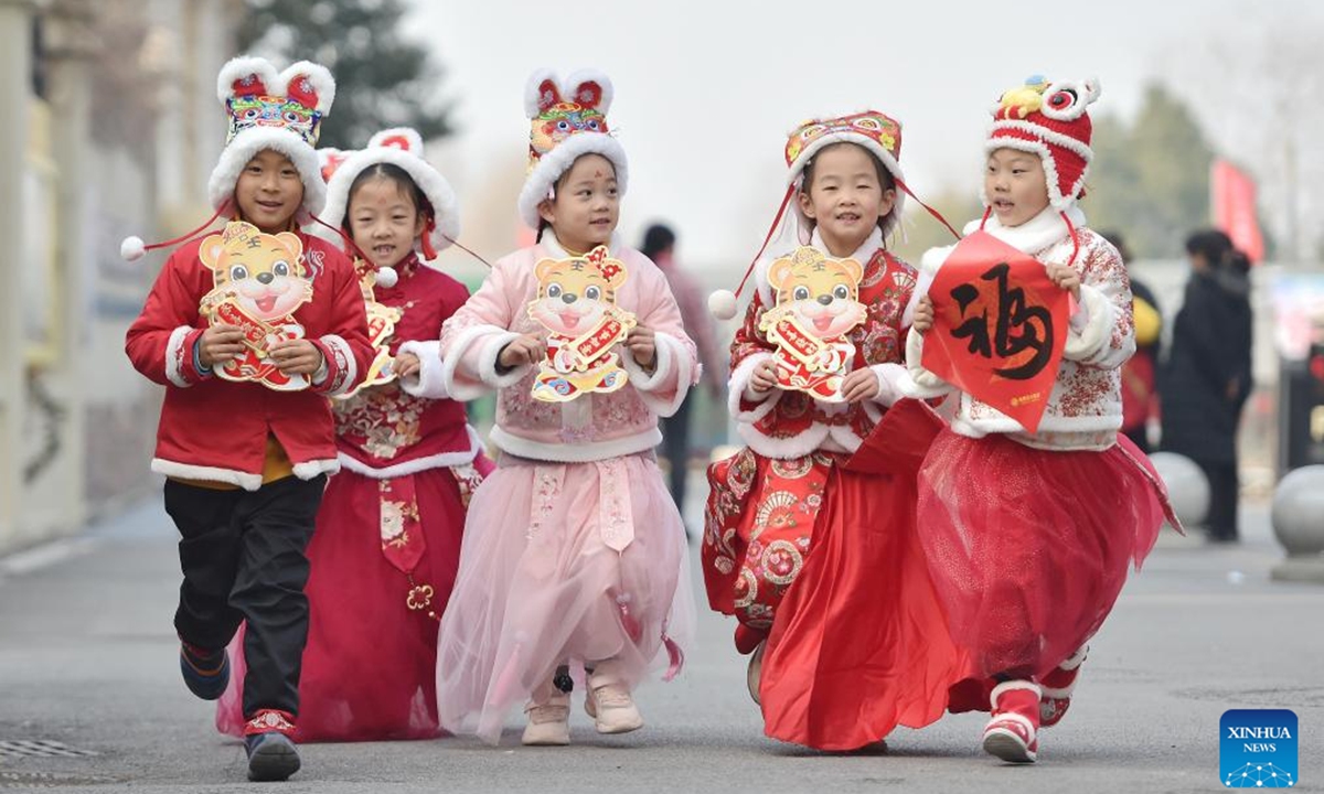 Children wearing tiger-themed hats are seen with decorations on their hands in Hefei, east China's Anhui Province, Jan. 18, 2022. With the arrival of Chinese New Year on Tuesday, the country enters the Year of the Tiger.