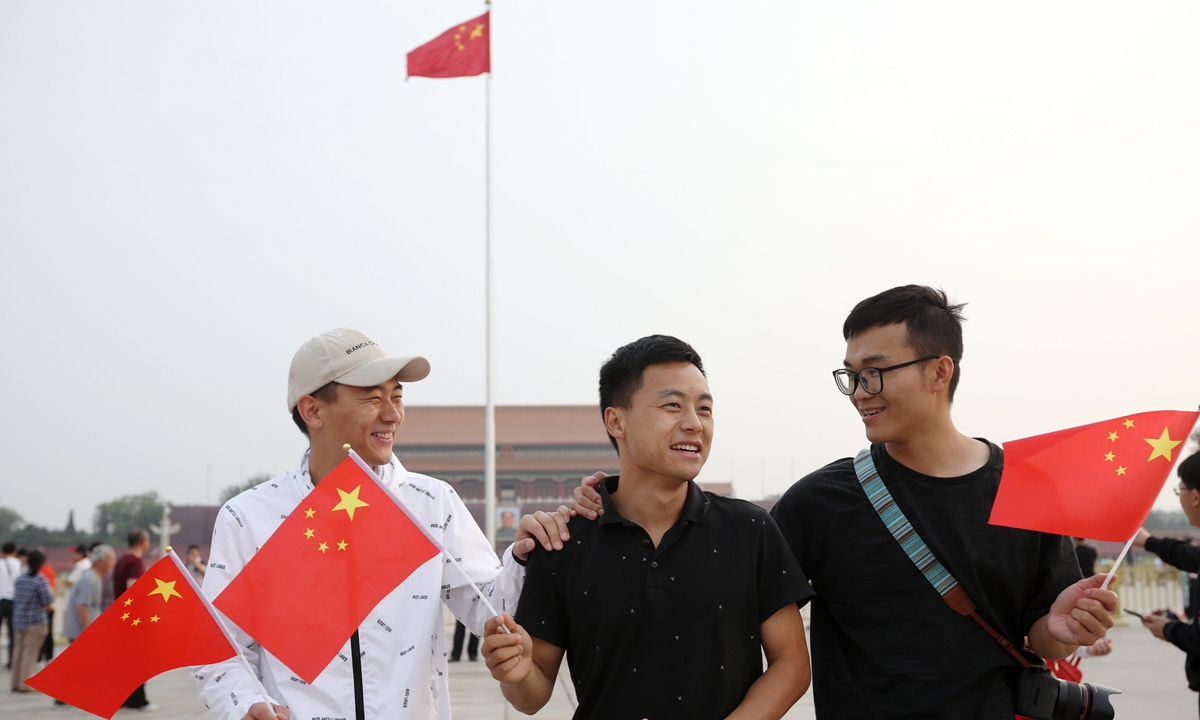 Three men hold Chinese national flags at Tiananmen Square in Beijing on Tuesday after the flag-raising ceremony. Photo: Cui Meng/GT