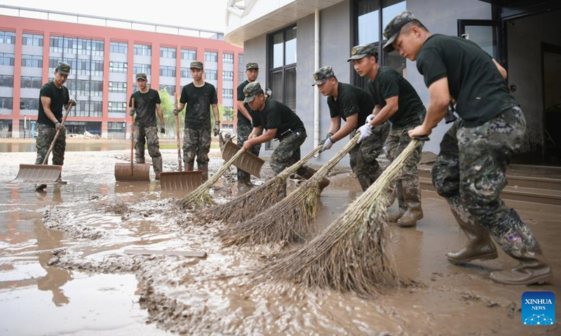 Members of the armed police force clean up sludge left after the flood caused by rainstorms brought by Typhoon Doksuri at the teaching building of a high school in Zhuozhou, north China's Hebei Province, Aug. 10, 2023.(Photo: Xinhua)