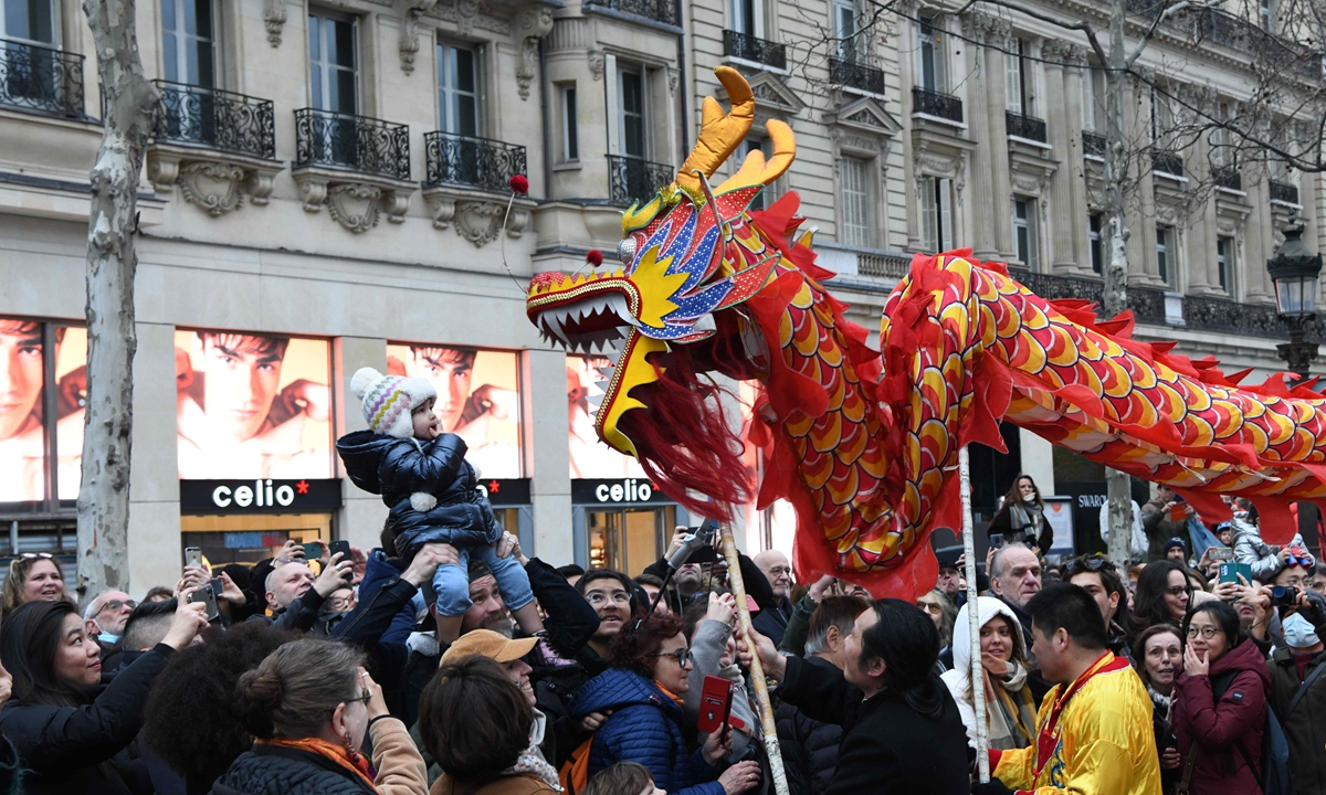 Parisians interact with a dancing dragon sending Chinese New Year wishes to the public on the Champs-Elysees avenue on February 4, 2024 during a street celebration for the upcoming Year of the Dragon. Photo: cnsphoto