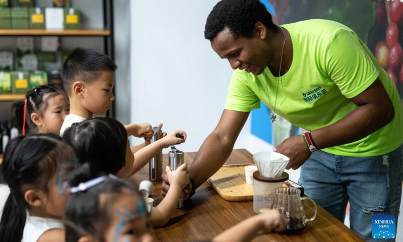 A volunteer grinds coffee beans with children during a hands-on experience session at the Ethiopia pavilion of a permanent exhibition hall of the China-Africa Economic and Trade Cooperation Promotion Innovation Demonstration Park in Changsha, central China's Hunan Province, Aug. 30, 2024. Various activities promoting youth communication between China and Africa were organized here during the summer vacation. With the help of African volunteers from local universities, Chinese students were able to feel the charm of African culture by learning traditional African dance, music, folk arts, and making immersive tours of African customs via VR devices.  Photo: Xinhua