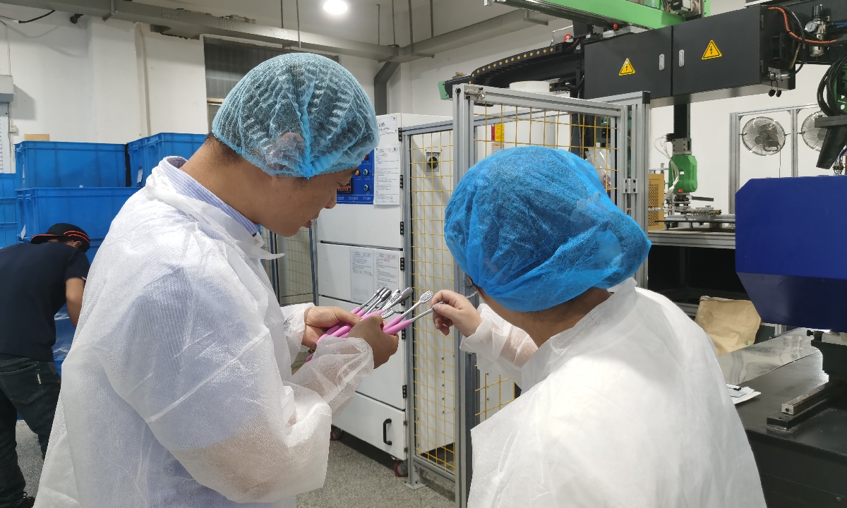 Tu Xinye (left), the manager of Shuguang Toothbrush Factory, checks whether the quality of the freshly produced toothbrushes on the production line is up to standard. Photo: Hu Yuwei/GT