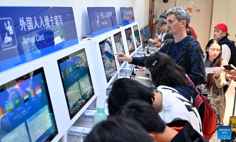 Tourists from Singapore fill in digital arrival cards at the Meilan International Airport in Haikou, south China's Hainan Province, Dec. 28, 2024.