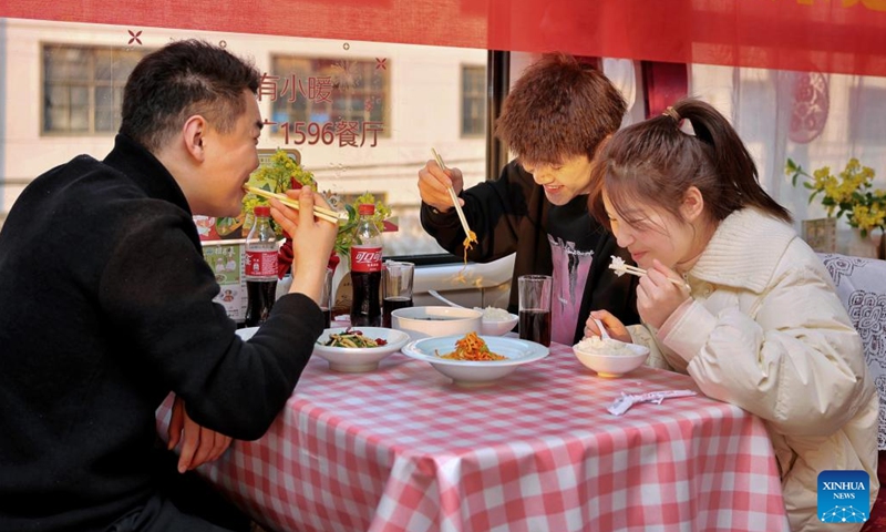 Passengers dine aboard train K212 which travels from Ningbo, east China's Zhejiang Province, to Guangzhou, south China's Guangdong Province, Jan. 13, 2025. As this year's Spring Festival travel rush began on Jan. 14, the Hangzhou passenger service unit of China Railway Shanghai Bureau Group Co., Ltd. has prioritized the improvement of passenger experience. Various efforts have been made, including arranging train chef exchanges, rolling out new dishes, and providing food order and delivery services. (Xinhua/Jiang Han)