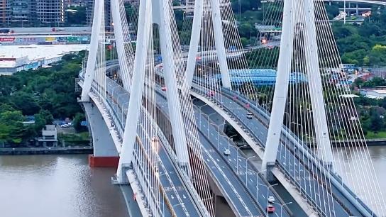 Vehicles cross Luoxi Bridge as ships sail along Pearl River