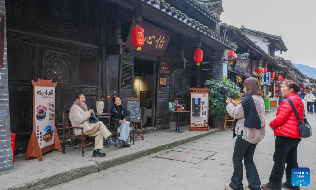 Tourists pose for photos in Zhaohua ancient town in Zhaohua District of Guangyuan City, southwest China's Sichuan Province, Dec. 13, 2025. Zhaohua ancient town, located in Guangyuan City of southwest China's Sichuan Province, sits at the confluence of the Bailong River, the Jialing River, and the Qingjiang River. As a well-preserved ancient town, it carries a history of over 2,300 years.However, due to old infrastructure and unplanned construction, the ancient town once fell into disorder with residents living in the town having to undergo various difficulties. In order to refresh the ancient town, since 2012, Zhaohua District has launched a project to preserve the villages as a whole. While improving the village environment, the preservation project brings along local rural tourism, allowing the ancient town to be revitalized through preservation. (Xinhua/Wu Di)