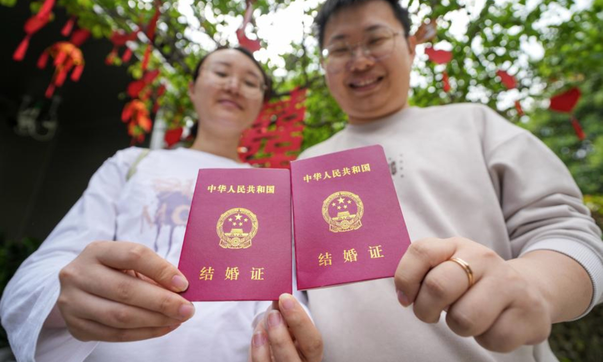 A couple poses for photos with their marriage certificates at a marriage registration office in the Xuanwu Lake Park in Nanjing, east China's Jiangsu Province, May 10, 2025. (Xinhua/Li Bo)